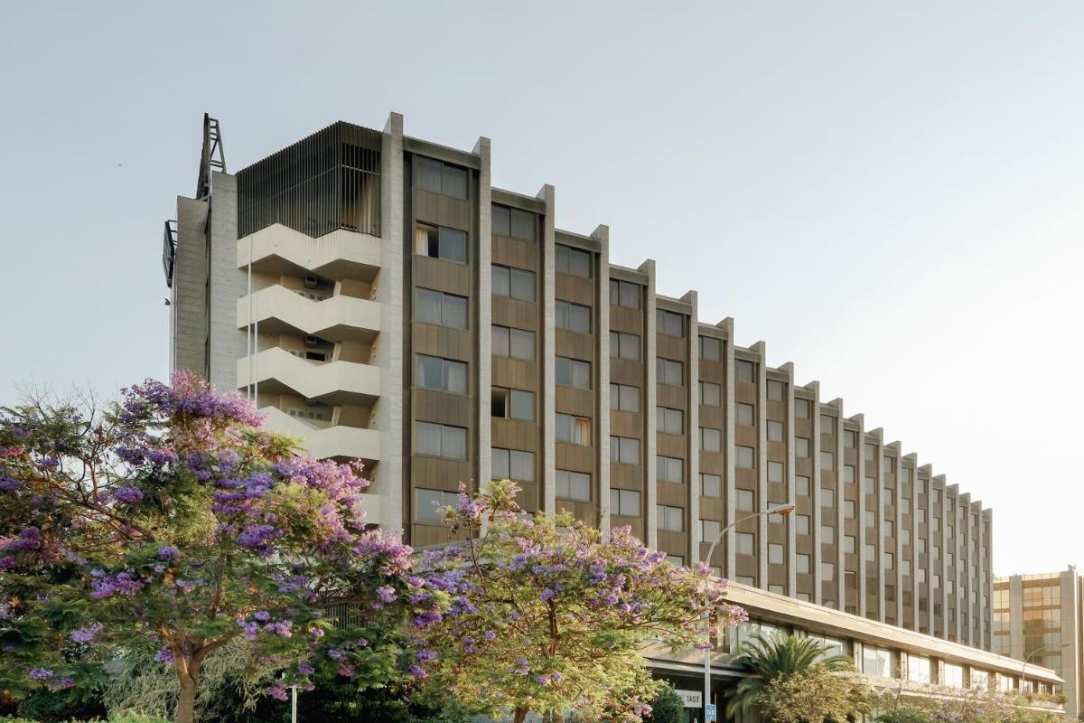 Un edificio alto con árboles delante. en Hesperia Barcelona Sant Just, en Sant Just Desvern