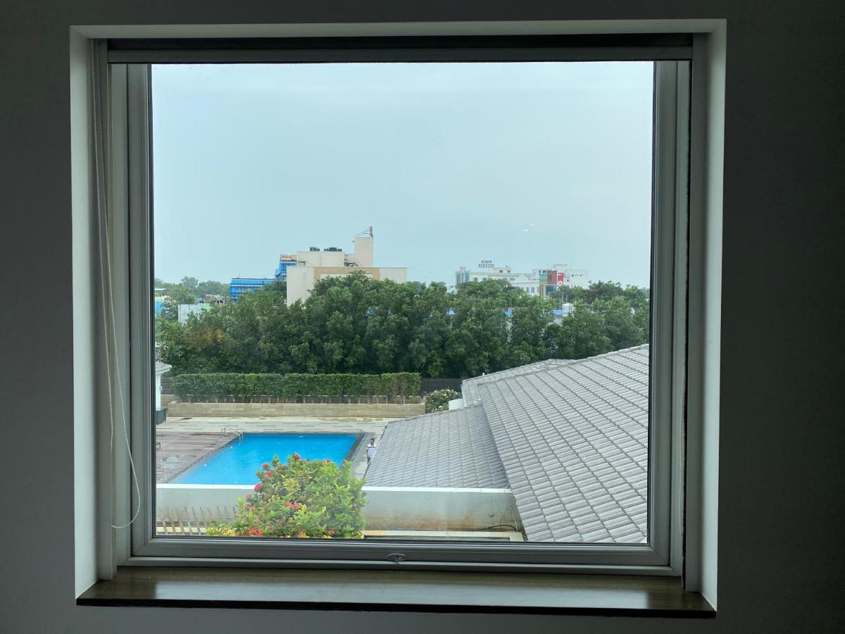 a window with a view of a swimming pool at The Residency Towers, Rameswaram in Rāmeswaram