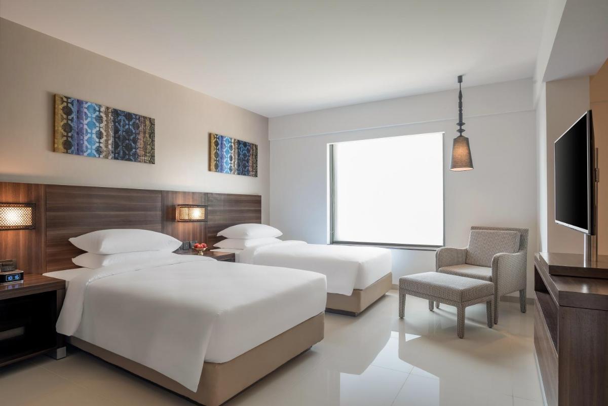 a bedroom with two beds and a flat screen tv at The Residency Towers, Rameswaram in Rāmeswaram