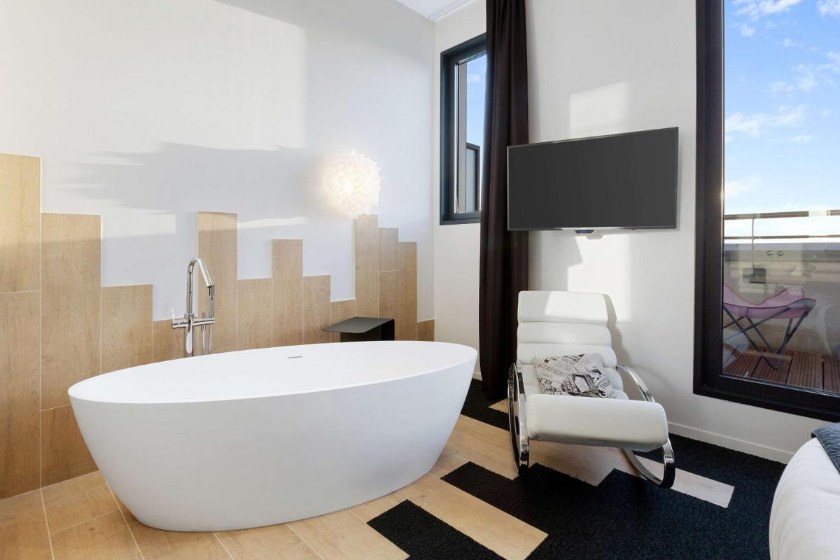 une salle de bains avec une grande baignoire blanche et une télévision dans l'établissement Best Western Plus Europe Hôtel Brest, à Brest