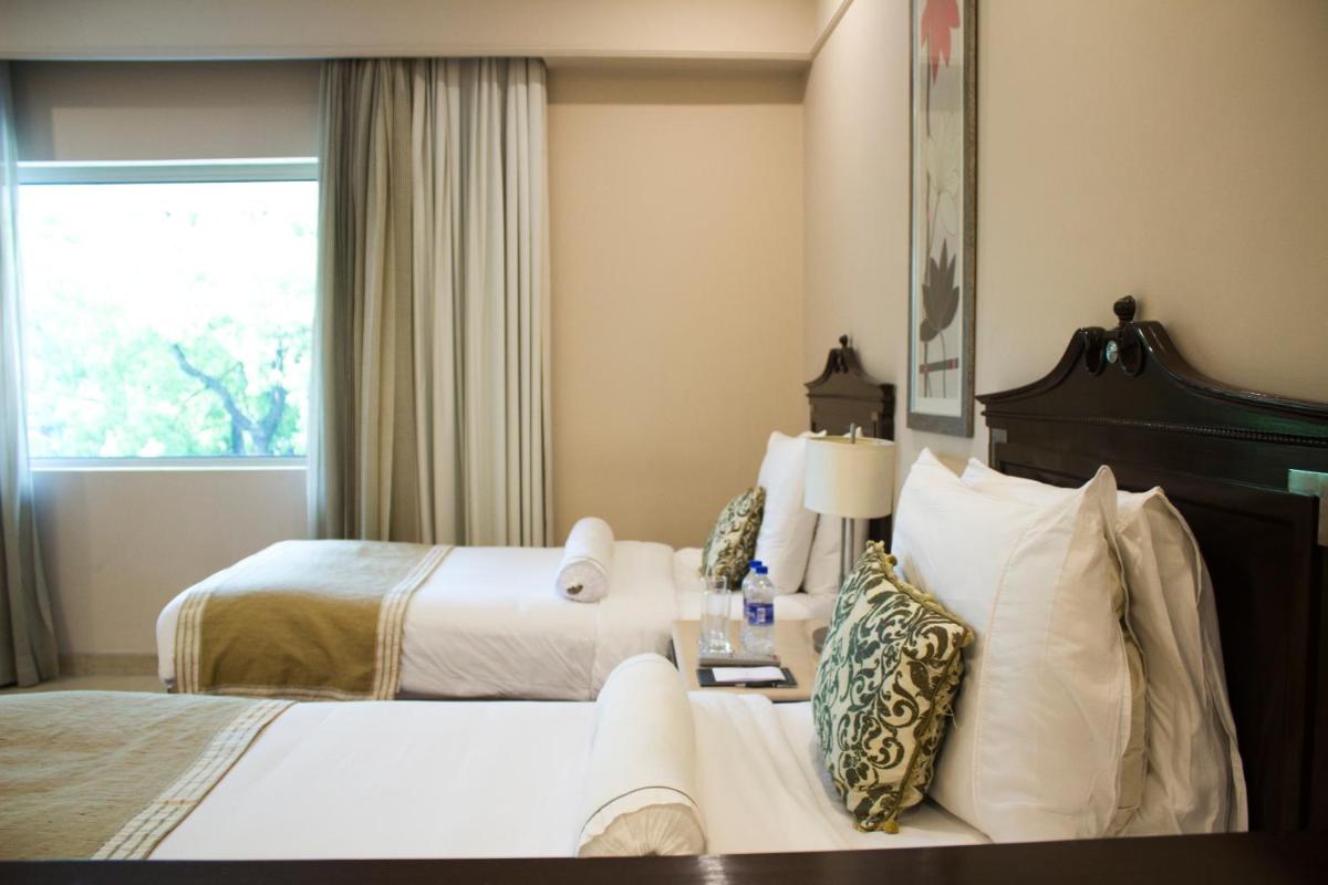 a hotel room with two beds and a window at The Claridges New Delhi in New Delhi a hotel room with two beds and a window at The Claridges New Delhi in New Delhi