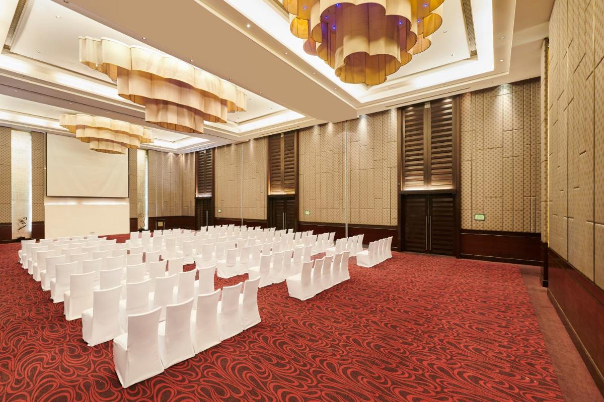 a conference room with rows of white chairs on a red carpet at Holiday Inn Mumbai International Airport by IHG in Mumbai