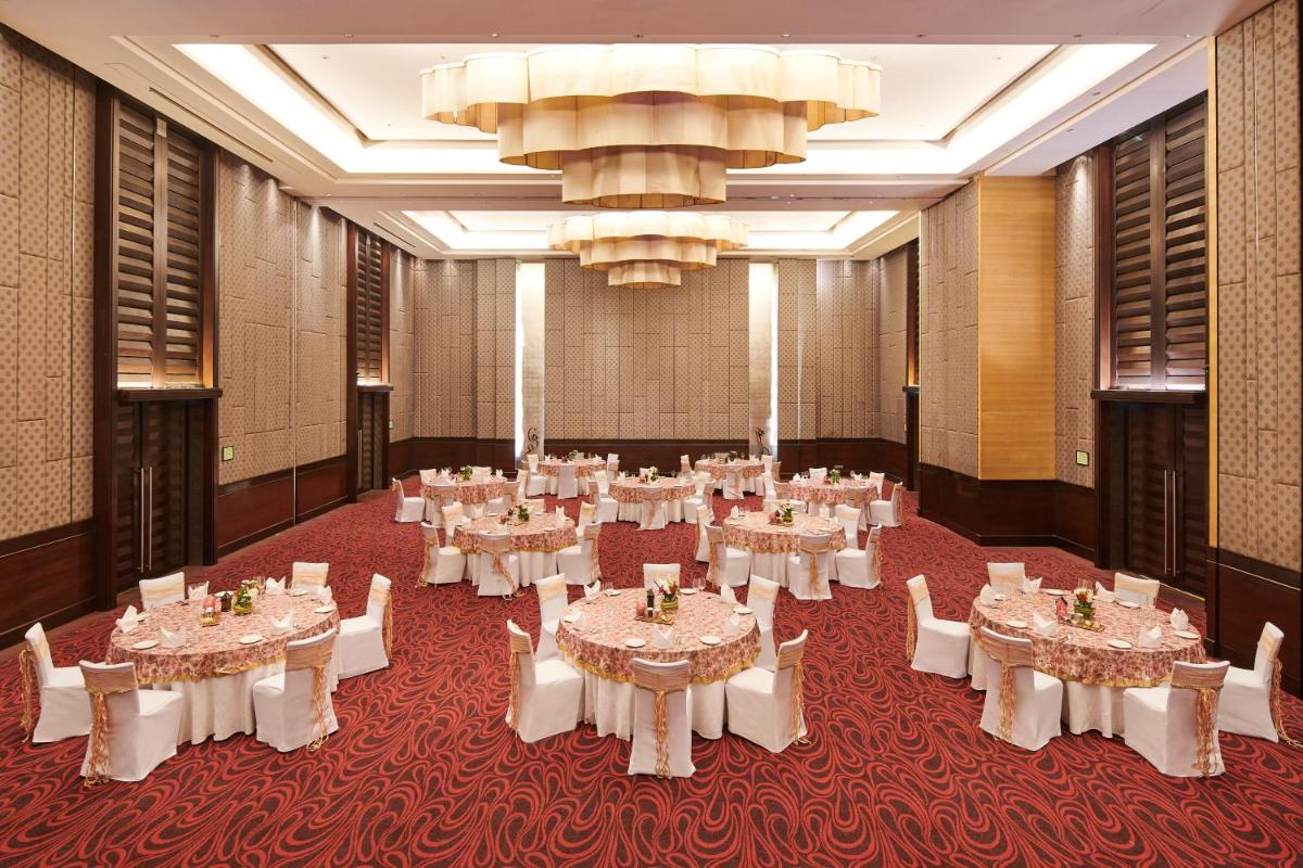 a banquet hall with white tables and chairs and a chandelier at Holiday Inn Mumbai International Airport by IHG in Mumbai