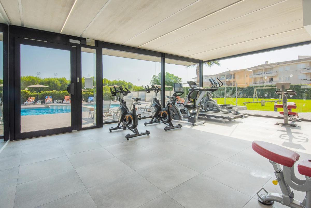 Un gimnasio con cintas de correr y elípticas en un edificio. en Aparthotel Dunes Platja, en Can Picafort