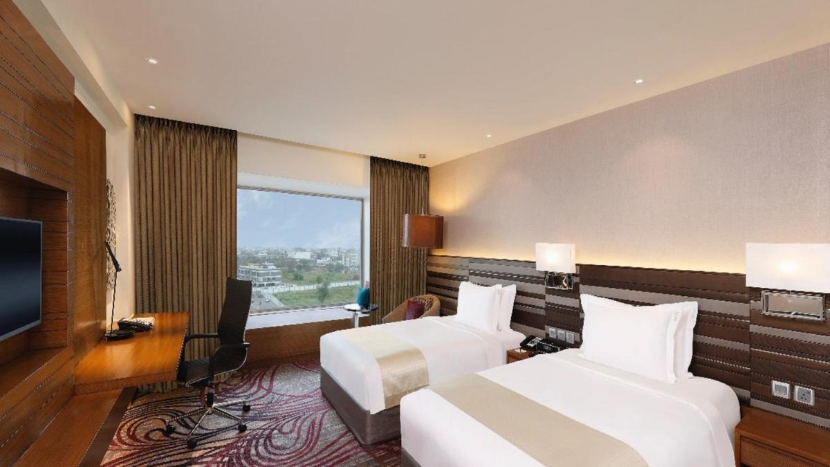 a hotel room with two beds and a television at Holiday Inn Jaipur City Centre by IHG in Jaipur a hotel room with two beds and a television at Holiday Inn Jaipur City Centre by IHG in Jaipur