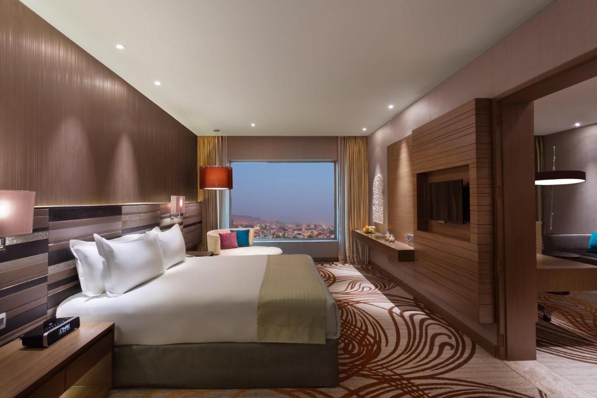 a hotel room with a bed and a large window at Holiday Inn Jaipur City Centre by IHG in Jaipur a hotel room with a bed and a large window at Holiday Inn Jaipur City Centre by IHG in Jaipur