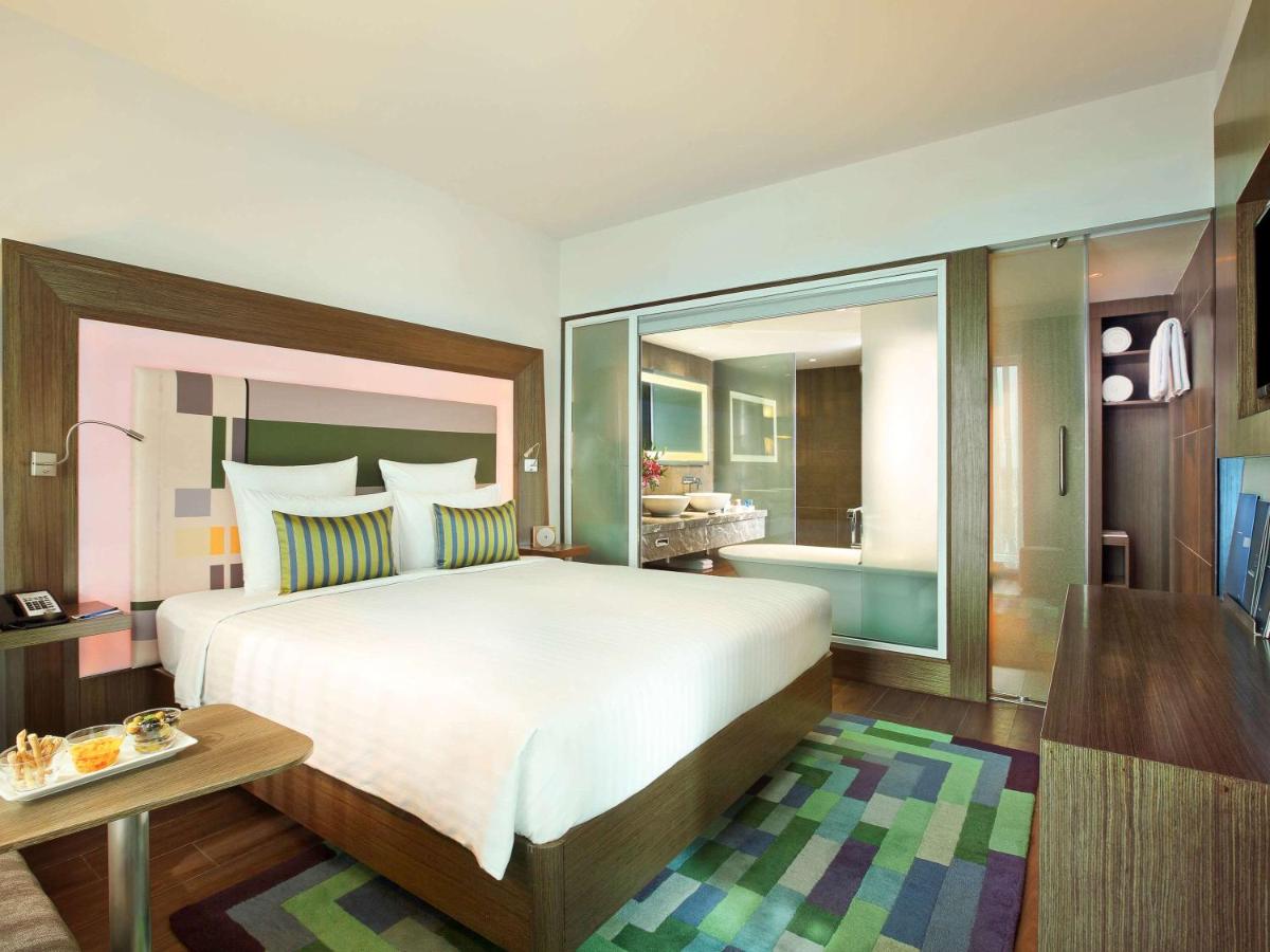 a bedroom with a large bed and a bathroom at Novotel Chennai Sipcot in Chennai
