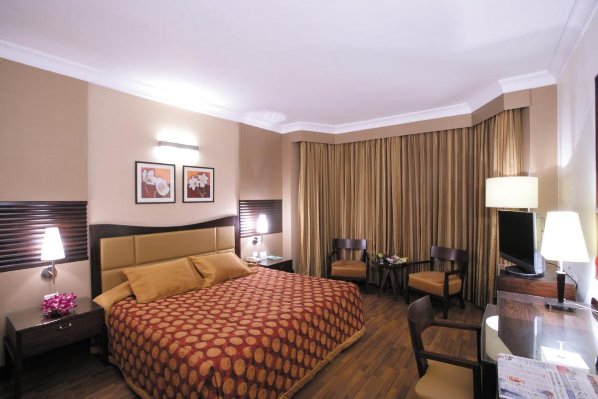 a bedroom with a bed and a desk and a television at The Retreat Hotel & Convention Centre in Mumbai +45 photos