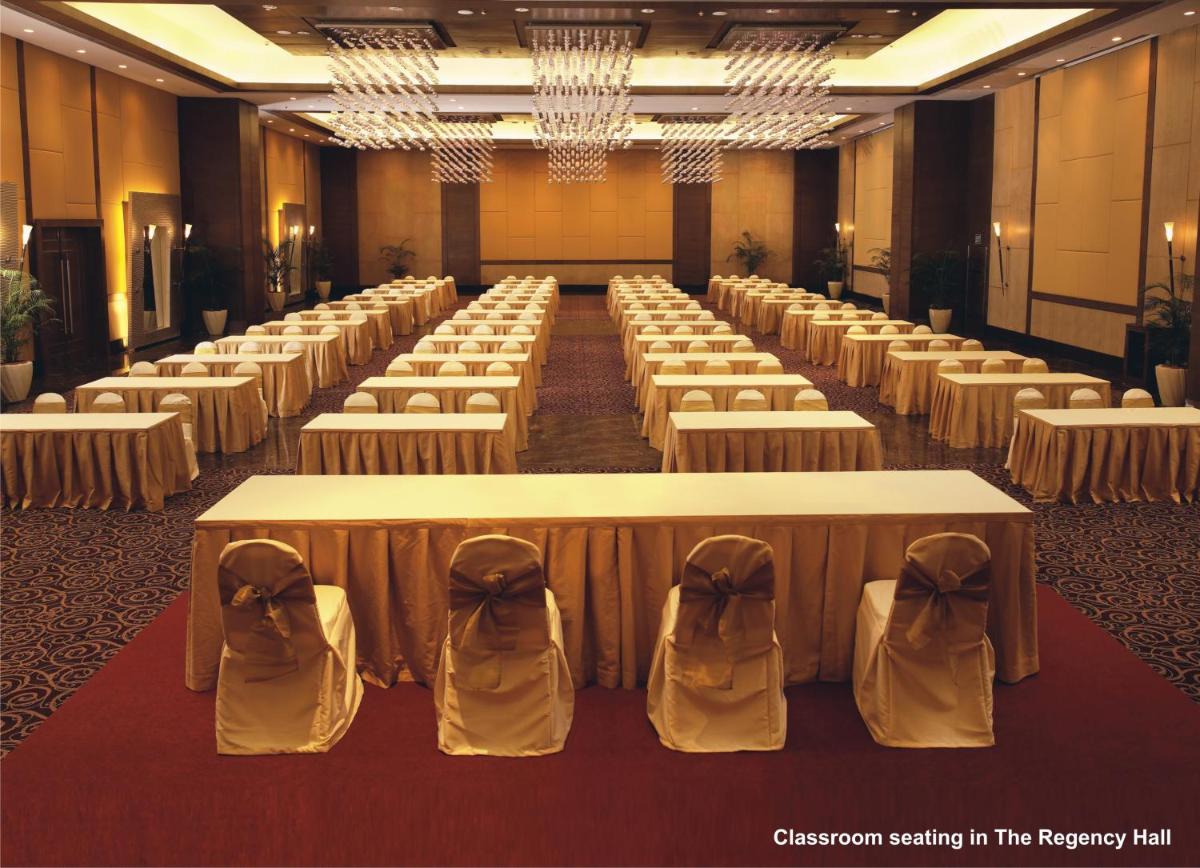 a large room with rows of tables and chairs at The Retreat Hotel & Convention Centre in Mumbai