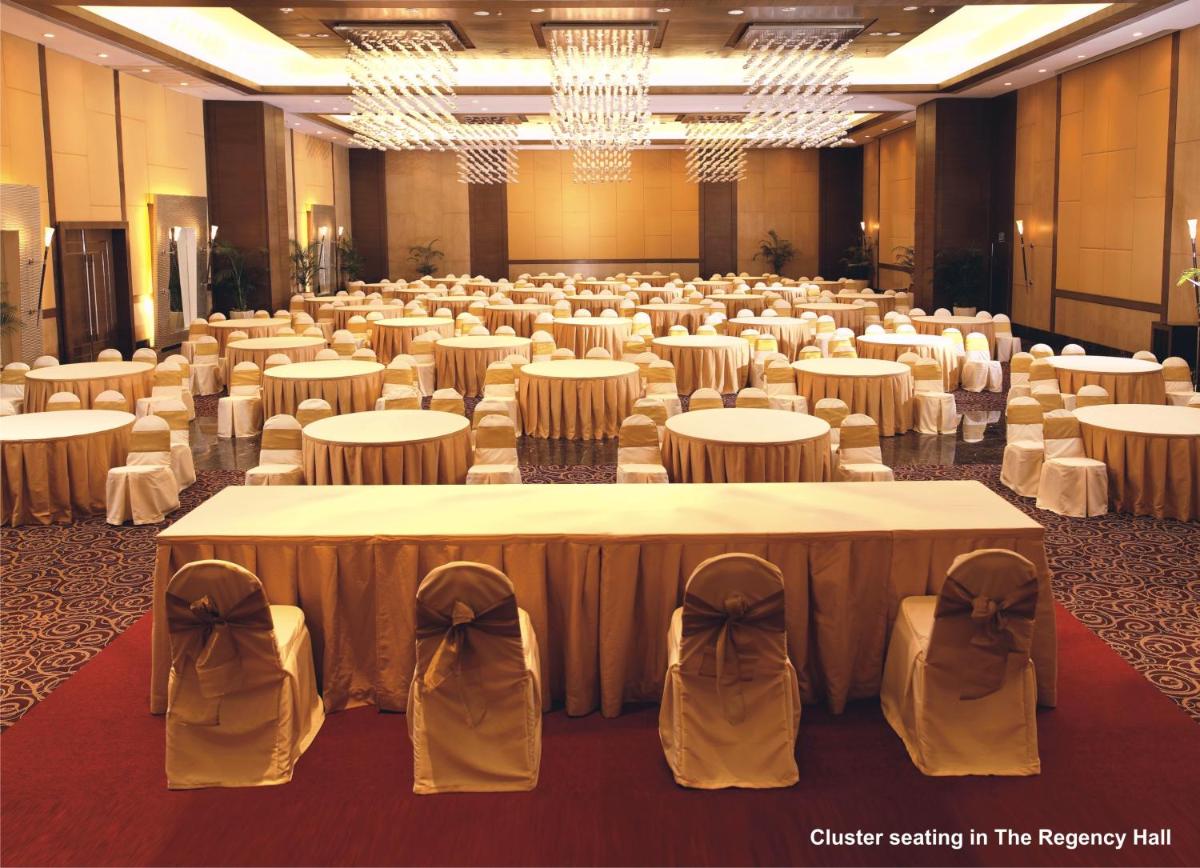 a large banquet hall with white tables and chairs at The Retreat Hotel & Convention Centre in Mumbai