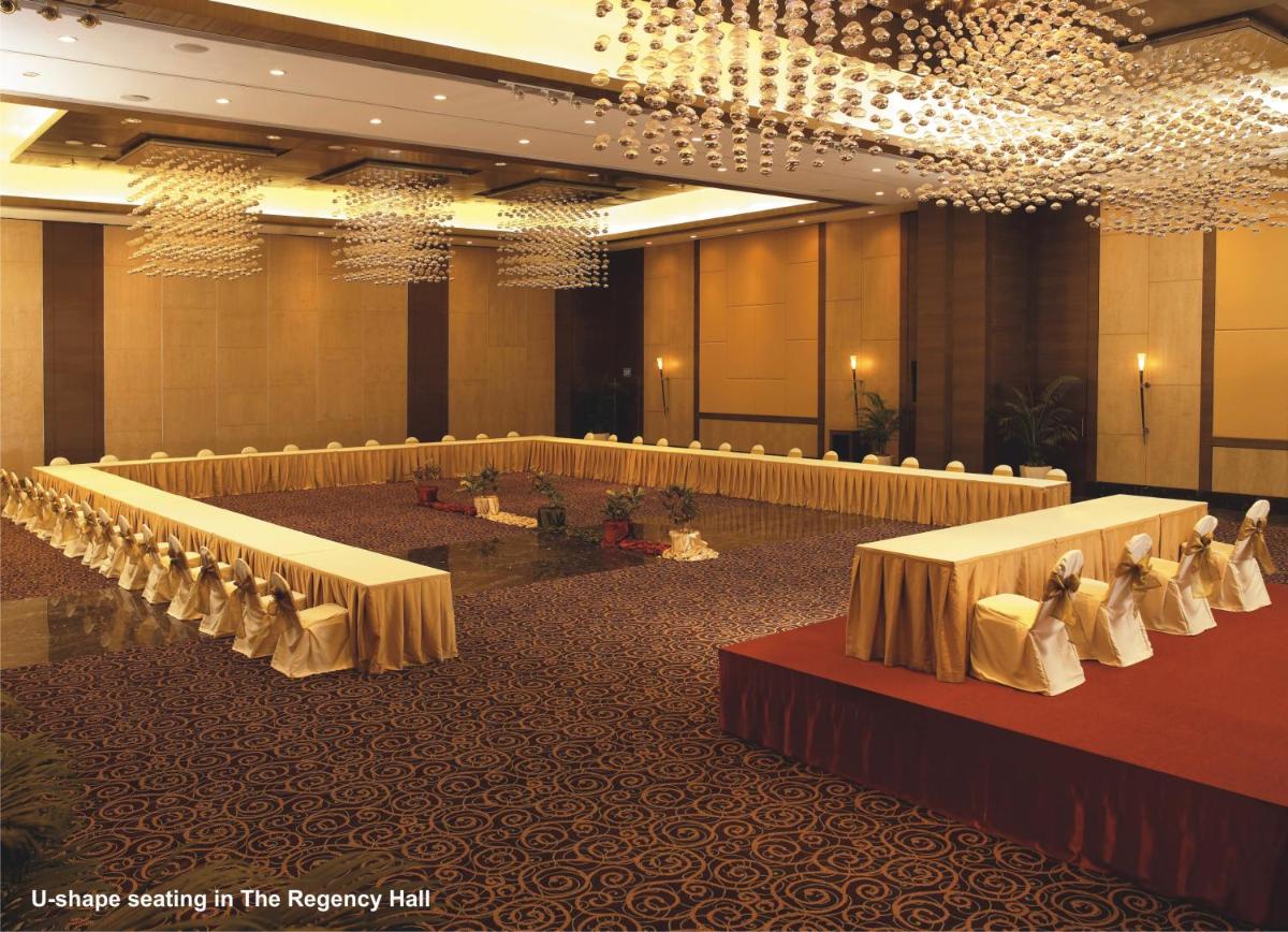 a banquet hall with rows of tables and chairs at The Retreat Hotel & Convention Centre in Mumbai