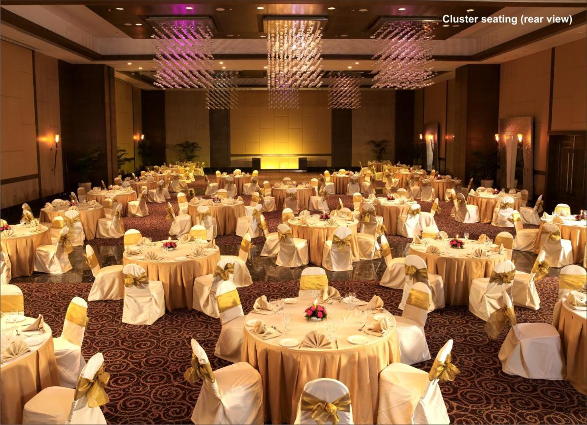 a large banquet hall with white tables and chairs at The Retreat Hotel & Convention Centre in Mumbai