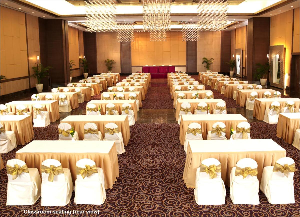 a large banquet hall with white tables and chairs at The Retreat Hotel & Convention Centre in Mumbai