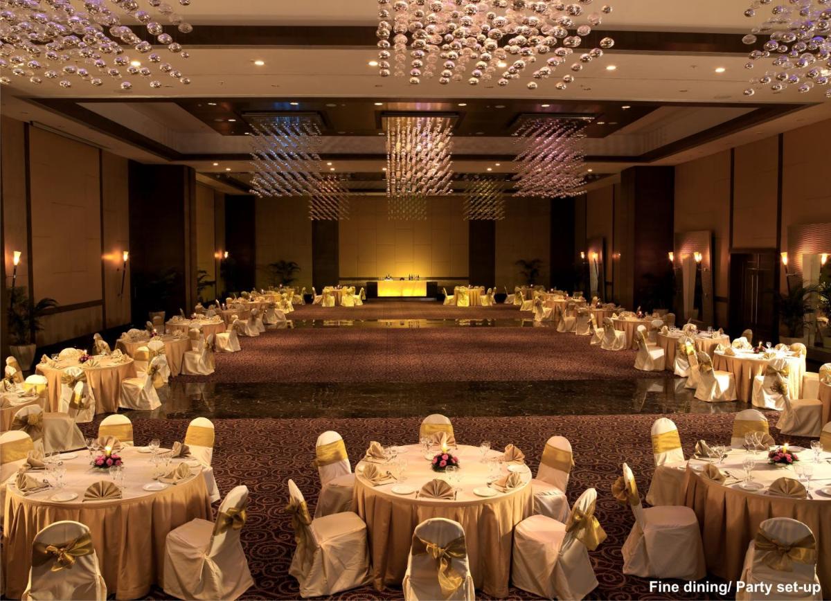 a large banquet hall with white tables and chairs at The Retreat Hotel & Convention Centre in Mumbai