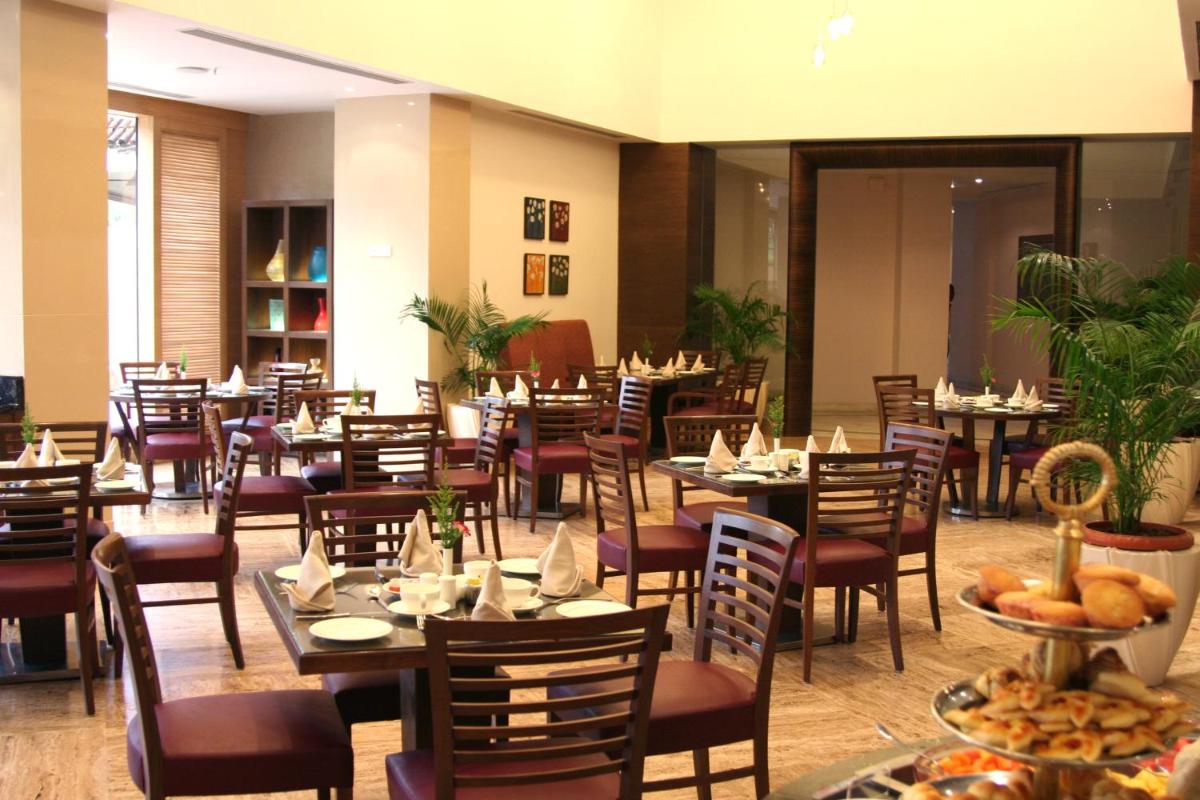a restaurant with tables and chairs with food on them at The Retreat Hotel & Convention Centre in Mumbai
