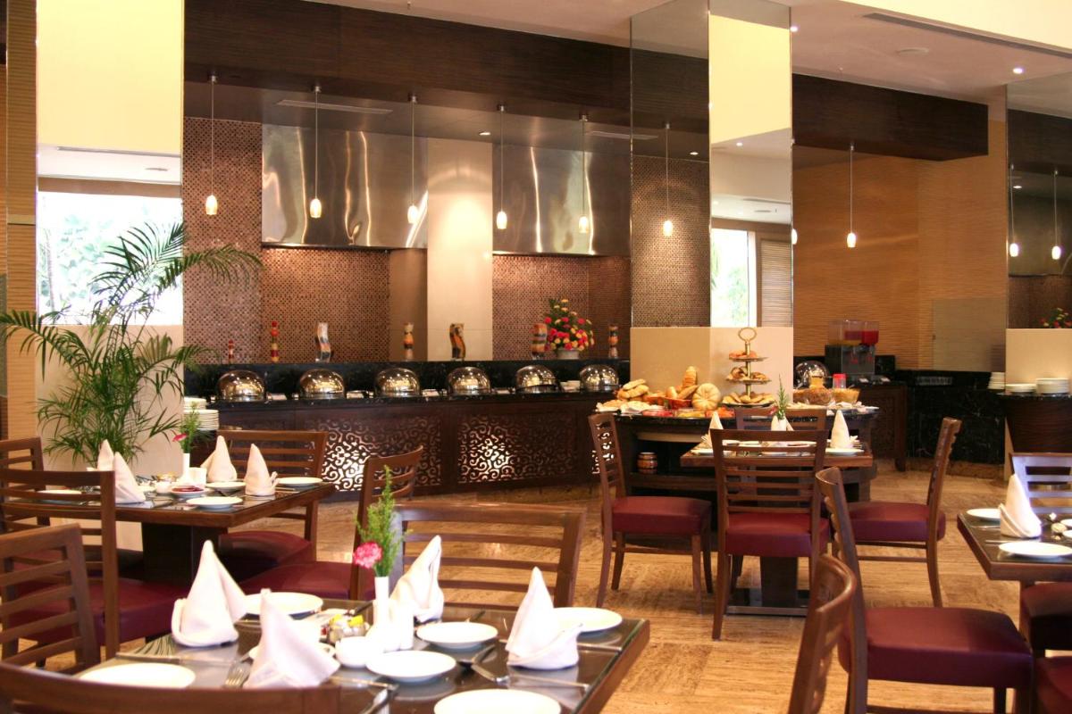 a dining room with tables and chairs in a restaurant at The Retreat Hotel & Convention Centre in Mumbai