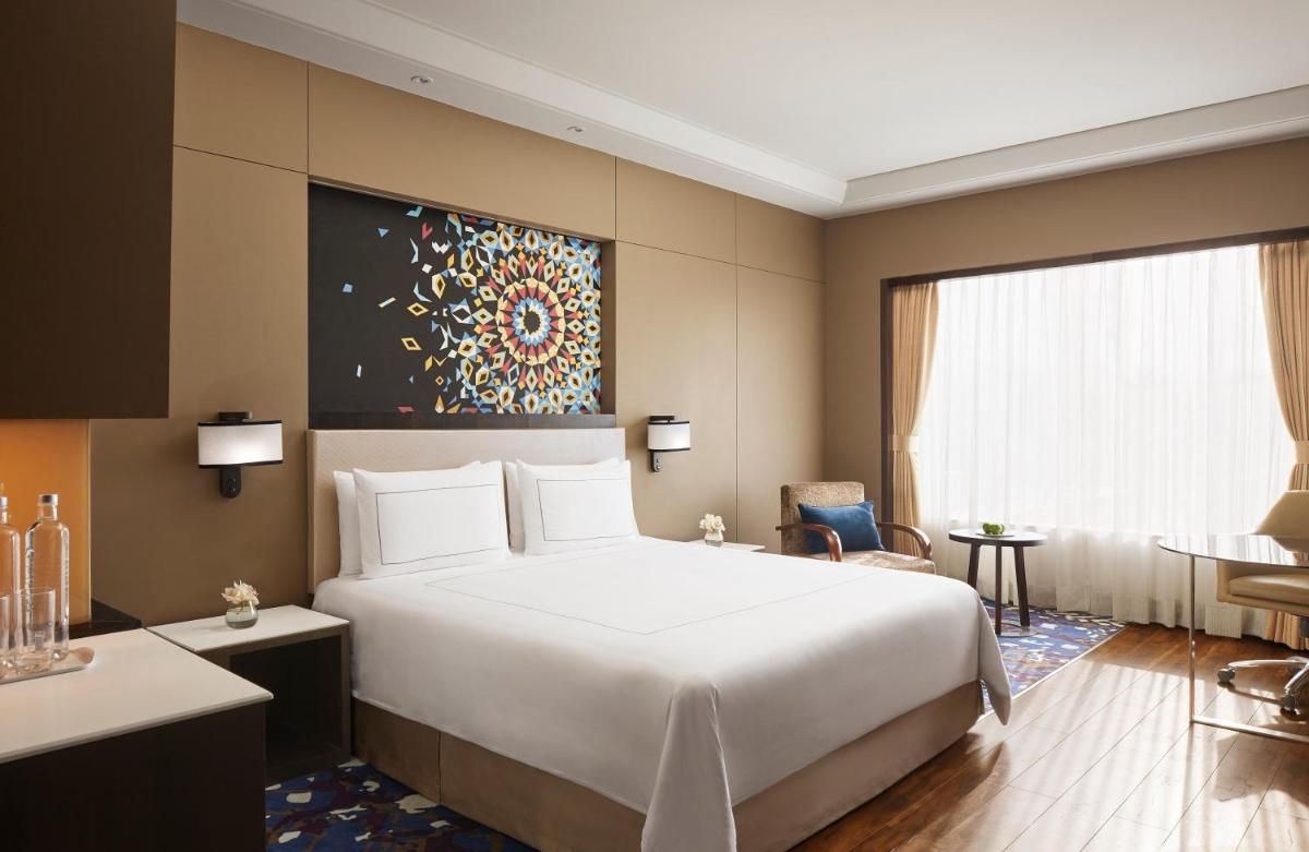 a hotel room with a large bed and a desk at Taj Agra in Agra