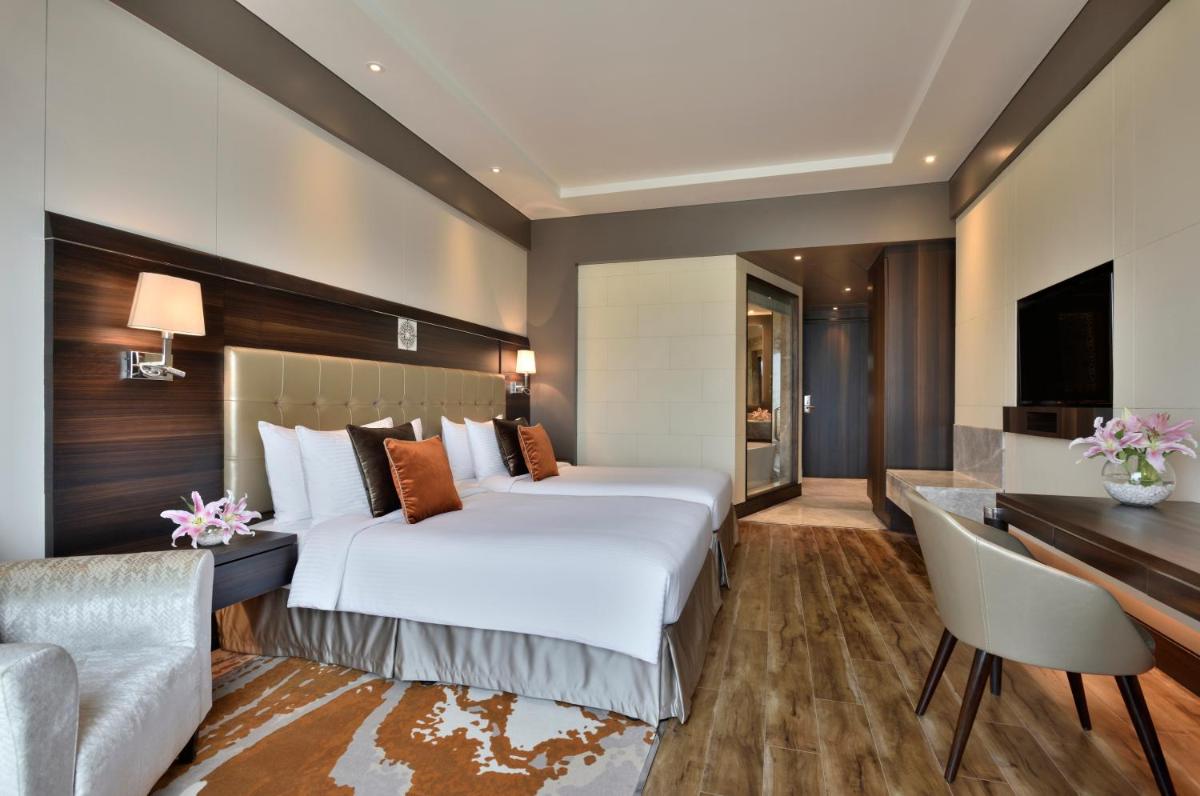 a hotel room with a large bed and a desk at Taj Agra in Agra