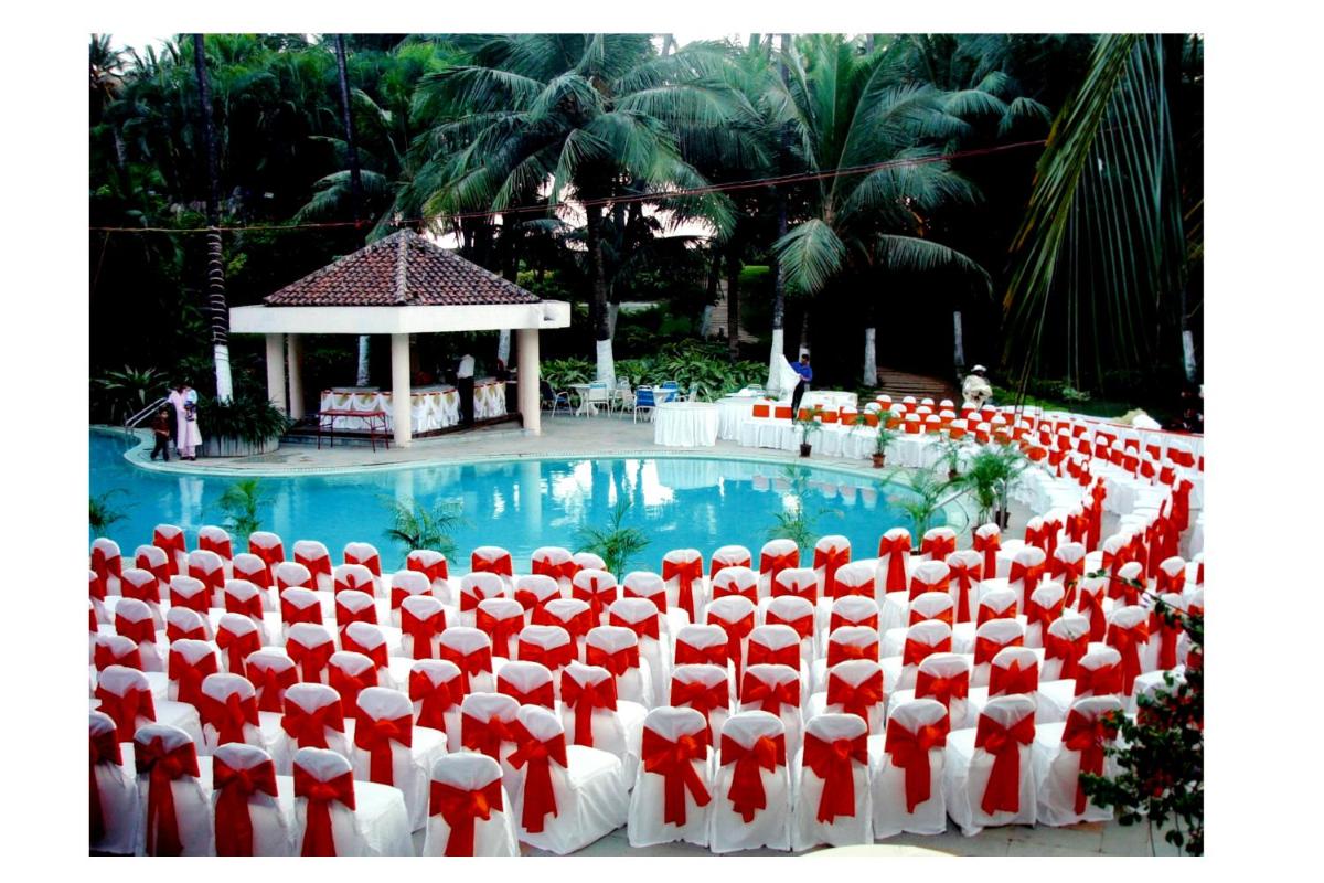 a group of red and white chairs in front of a pool at The Retreat Hotel & Convention Centre in Mumbai