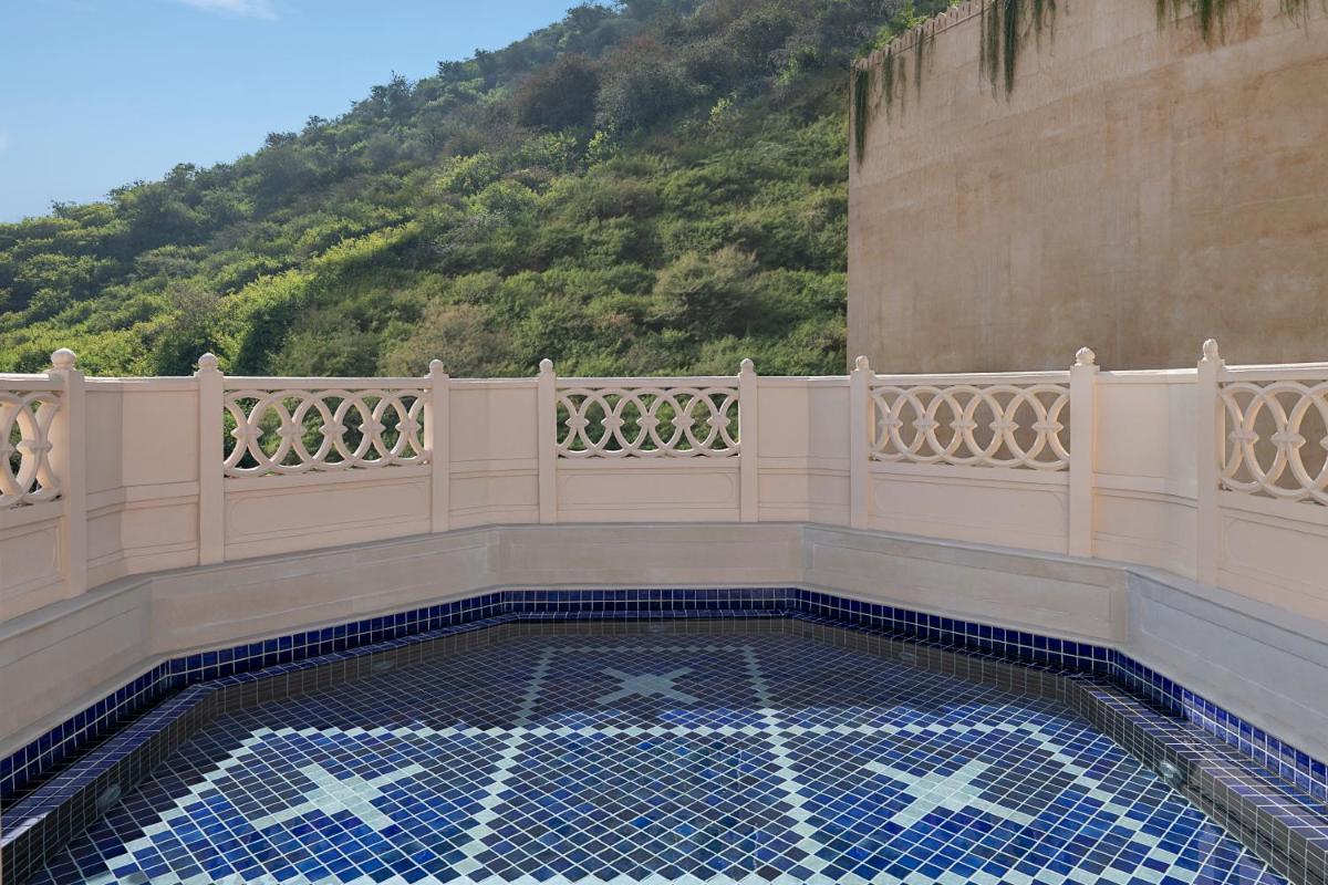 a balcony with a swimming pool in front of a mountain at Aurika, Udaipur - Luxury by Lemon Tree Hotels in Udaipur