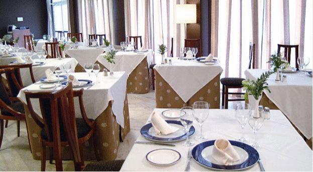 un comedor con mesas y sillas con mesas blancas y sillas en ARNOIA CALDARIA HOTEL Y BALNEARIO, en Arnoia 5 fotos más