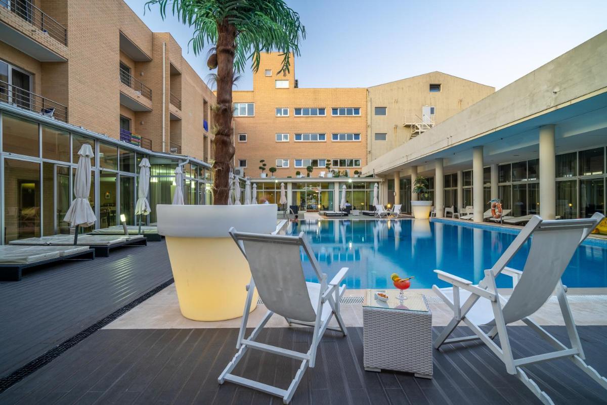 uma piscina com duas cadeiras e um hotel em Hotel de Ilhavo Plaza & Spa em Ílhavo