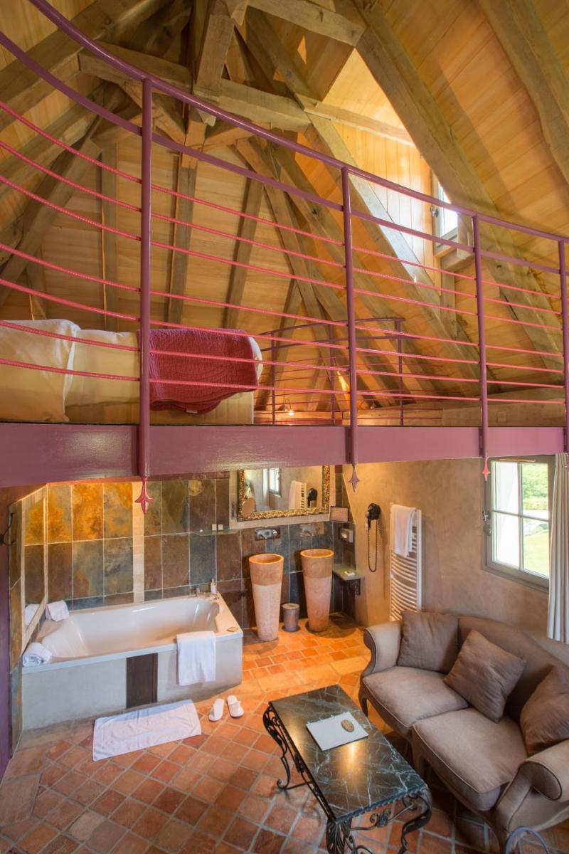 - un salon avec une mezzanine et une baignoire dans l'établissement Hôtel-Spa Le Saint Cirq, à Tour-de-Faure