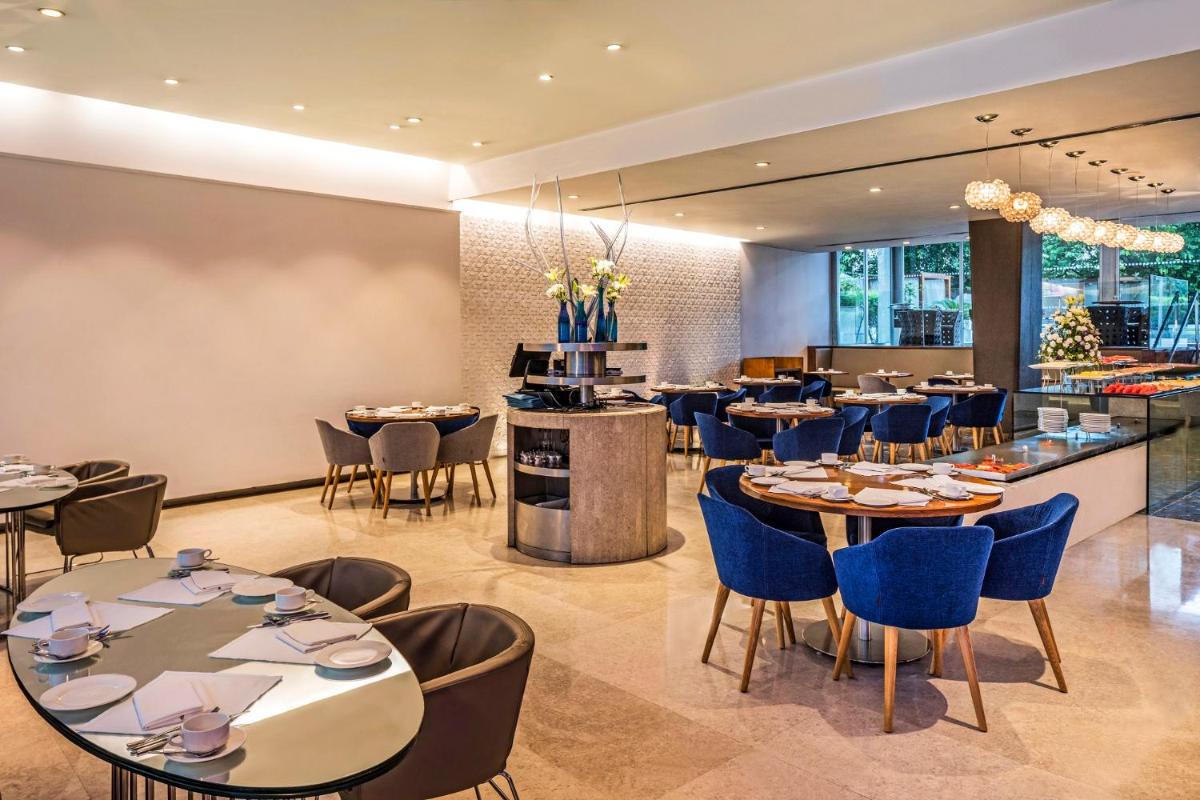 a restaurant with tables and chairs and a bar at The Park New Delhi in New Delhi a restaurant with tables and chairs and a bar at The Park New Delhi in New Delhi