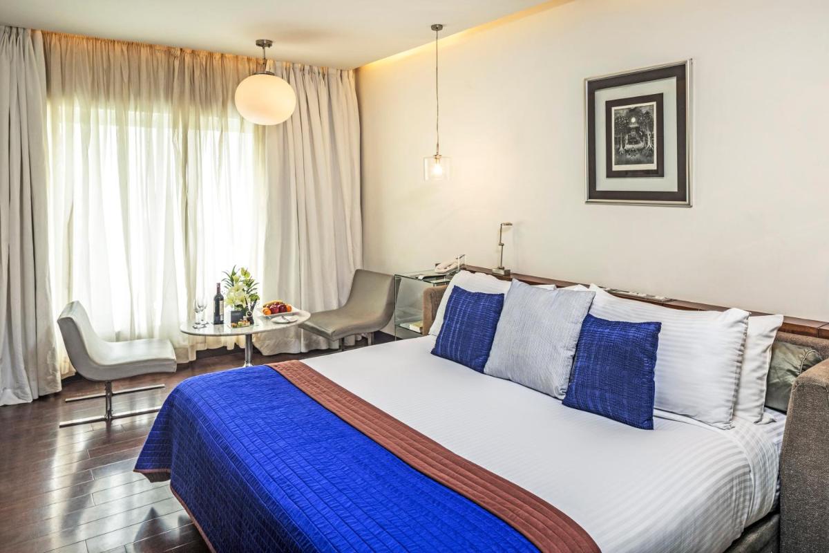a bedroom with a large bed with blue and white pillows at The Park New Delhi in New Delhi a bedroom with a large bed with blue and white pillows at The Park New Delhi in New Delhi
