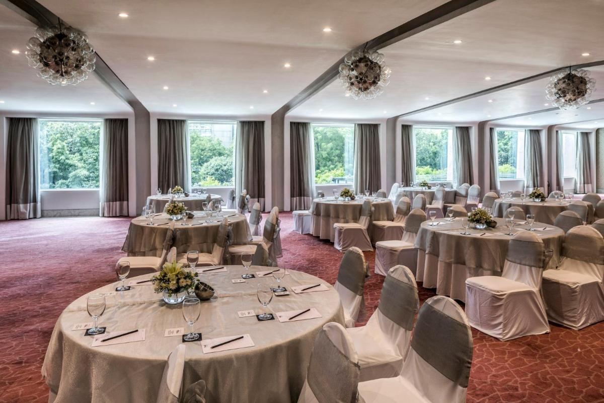 a room with tables and chairs in a room with windows at The Park New Delhi in New Delhi a room with tables and chairs in a room with windows at The Park New Delhi in New Delhi
