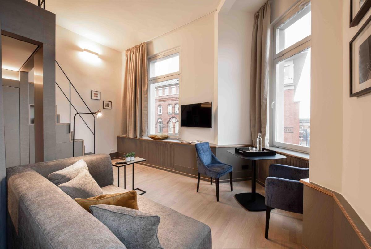 ein Wohnzimmer mit einer Couch, einem Tisch und einem Fenster in der Unterkunft OBERDECK Studio Apartments - Adults only in Hamburg ein Wohnzimmer mit einer Couch, einem Tisch und einem Fenster in der Unterkunft OBERDECK Studio Apartments - Adults only in Hamburg