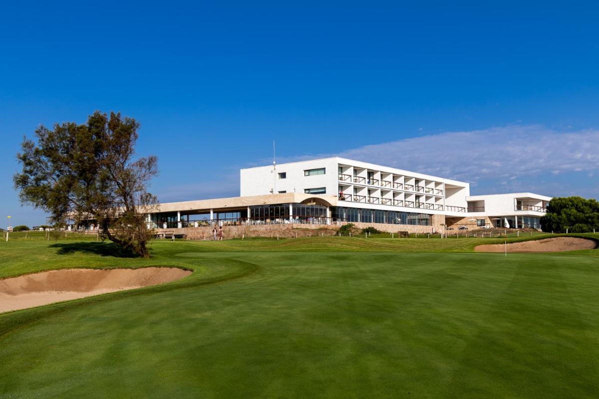 Una vista de un campo de golf con un edificio. en Parador de El Saler, en El Saler