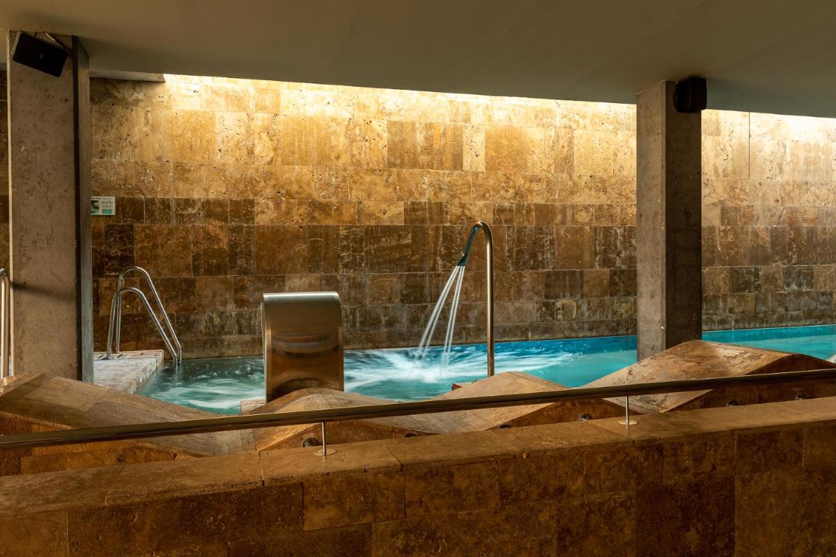 una gran piscina con una silla en el agua en Parador de El Saler, en El Saler