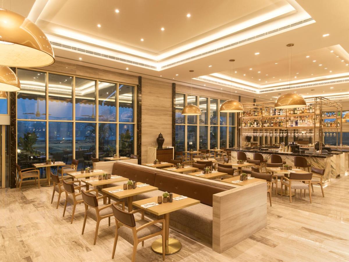 a restaurant with tables and chairs and large windows at Taj Palace, New Delhi in New Delhi a restaurant with tables and chairs and large windows at Taj Palace, New Delhi in New Delhi