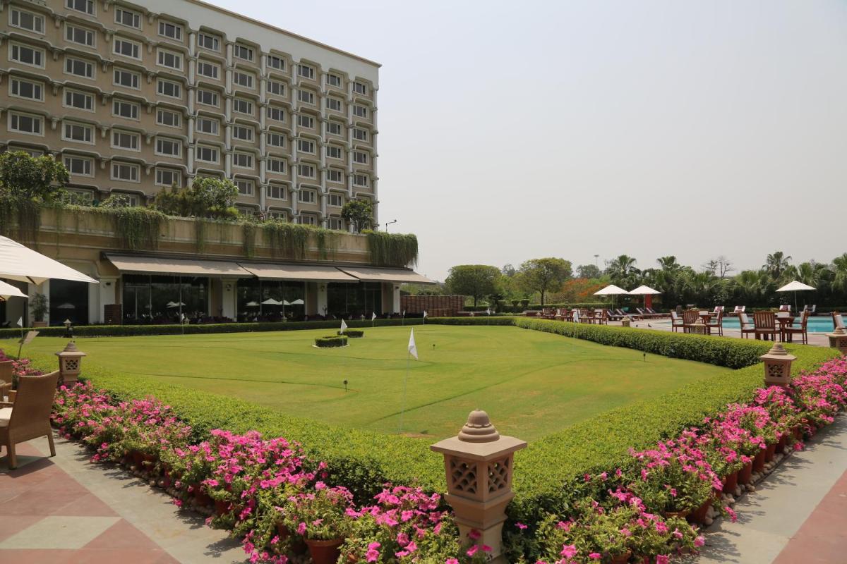 a hotel with a green lawn and pink flowers at Taj Palace, New Delhi in New Delhi a hotel with a green lawn and pink flowers at Taj Palace, New Delhi in New Delhi