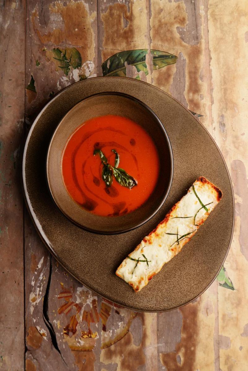 a plate with a bowl of soup and a slice of pizza at Taj Palace, New Delhi in New Delhi a plate with a bowl of soup and a slice of pizza at Taj Palace, New Delhi in New Delhi