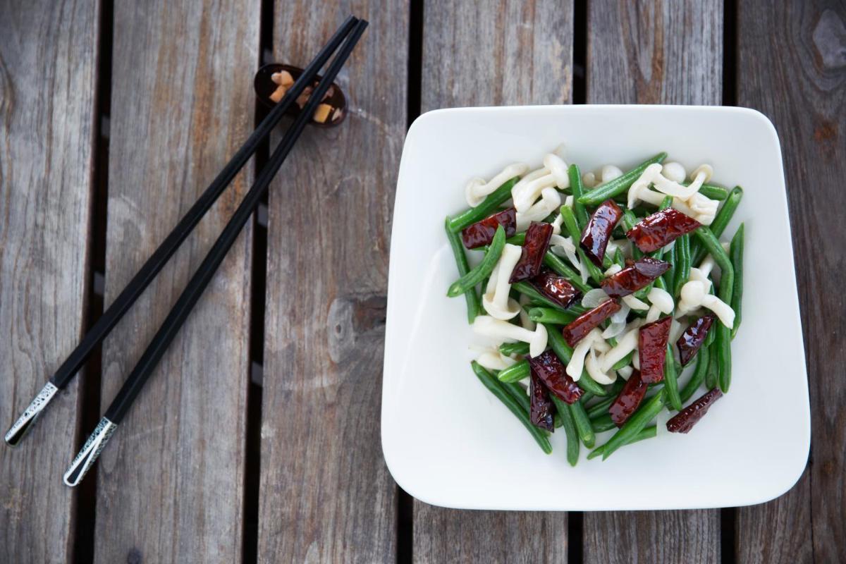 a white plate of food with green beans and chopsticks at Taj Palace, New Delhi in New Delhi a white plate of food with green beans and chopsticks at Taj Palace, New Delhi in New Delhi