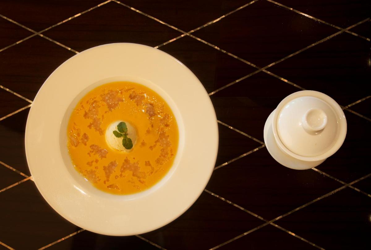 a bowl of soup on a table with a candle at Taj Palace, New Delhi in New Delhi a bowl of soup on a table with a candle at Taj Palace, New Delhi in New Delhi