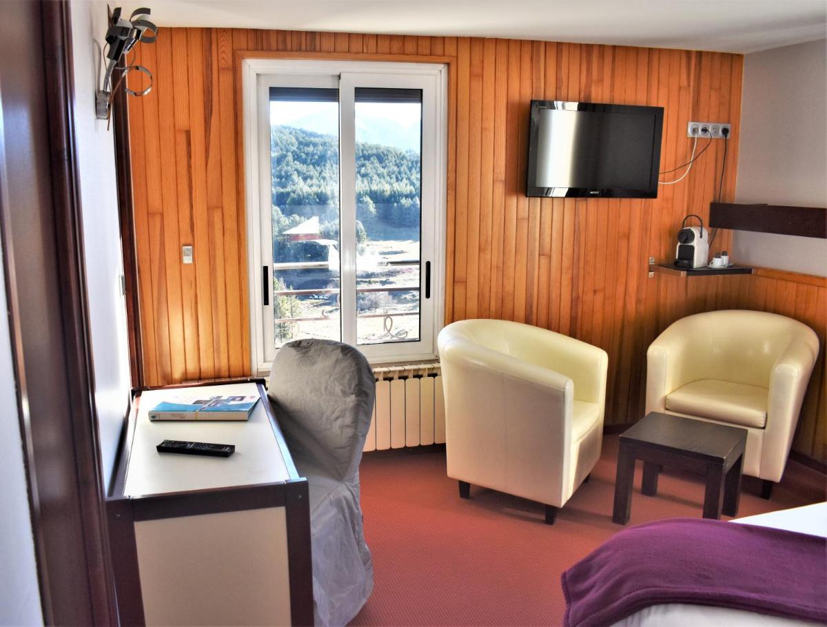 une chambre d'hôtel avec un lit, une table et des chaises dans l'établissement Hotel Corrieu, à La Llagonne