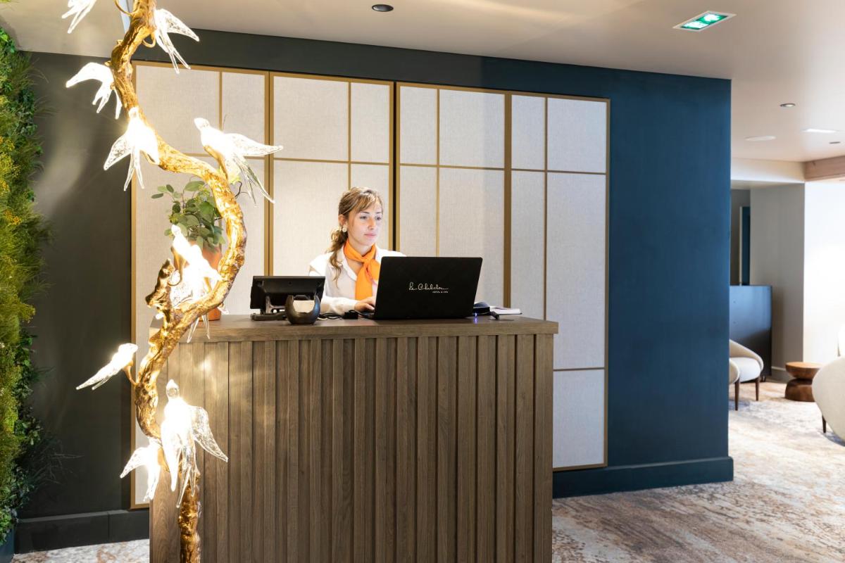une femme assise sur un bureau avec un ordinateur portable dans l'établissement Hotel Le Chabichou, à Courchevel 37 autres photos