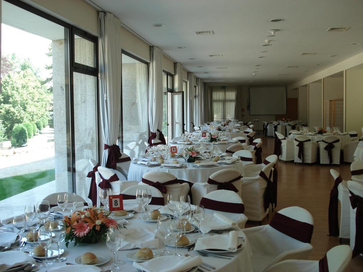 uma fila de mesas com toalhas de mesa e cadeiras brancas em Hotel Bienestar Termas de Moncao em Monção