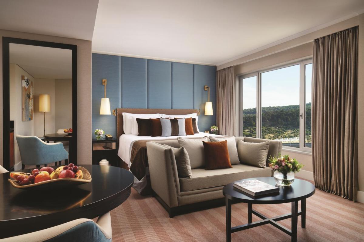 um quarto de hotel com uma cama, um sofá e uma mesa em Corinthia Lisbon em Lisboa