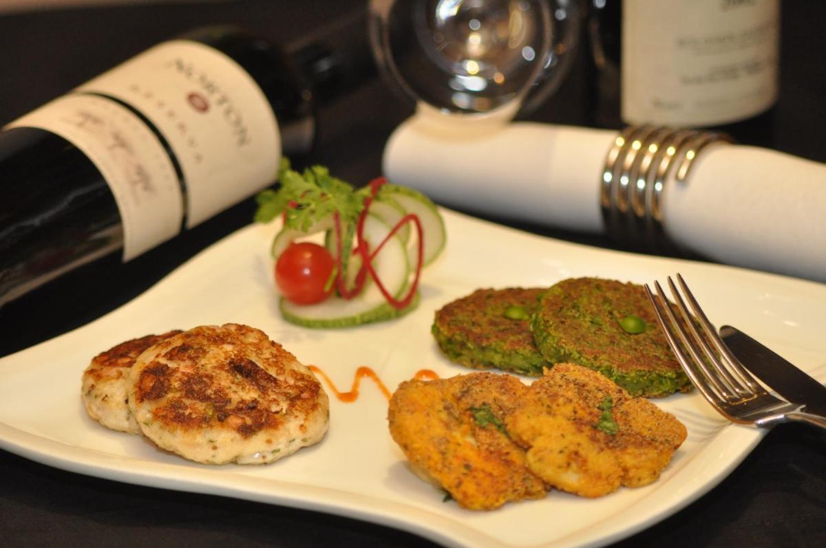 a white plate with food and a bottle of wine at Taj Palace, New Delhi in New Delhi a white plate with food and a bottle of wine at Taj Palace, New Delhi in New Delhi