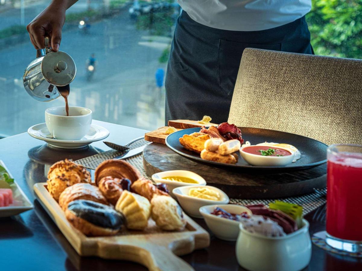 a table with a plate of food and a person pouring coffee at Mercure Hyderabad KCP Banjara Hills, An Accor Hotel in Hyderabad