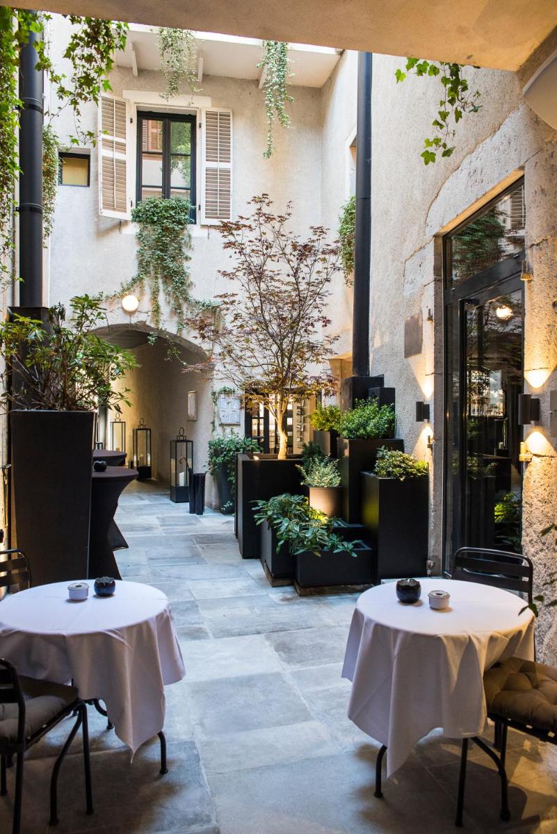 Deux tables et des chaises dans une cour avec des plantes dans l'établissement Petit Hôtel Confidentiel, à Chambéry