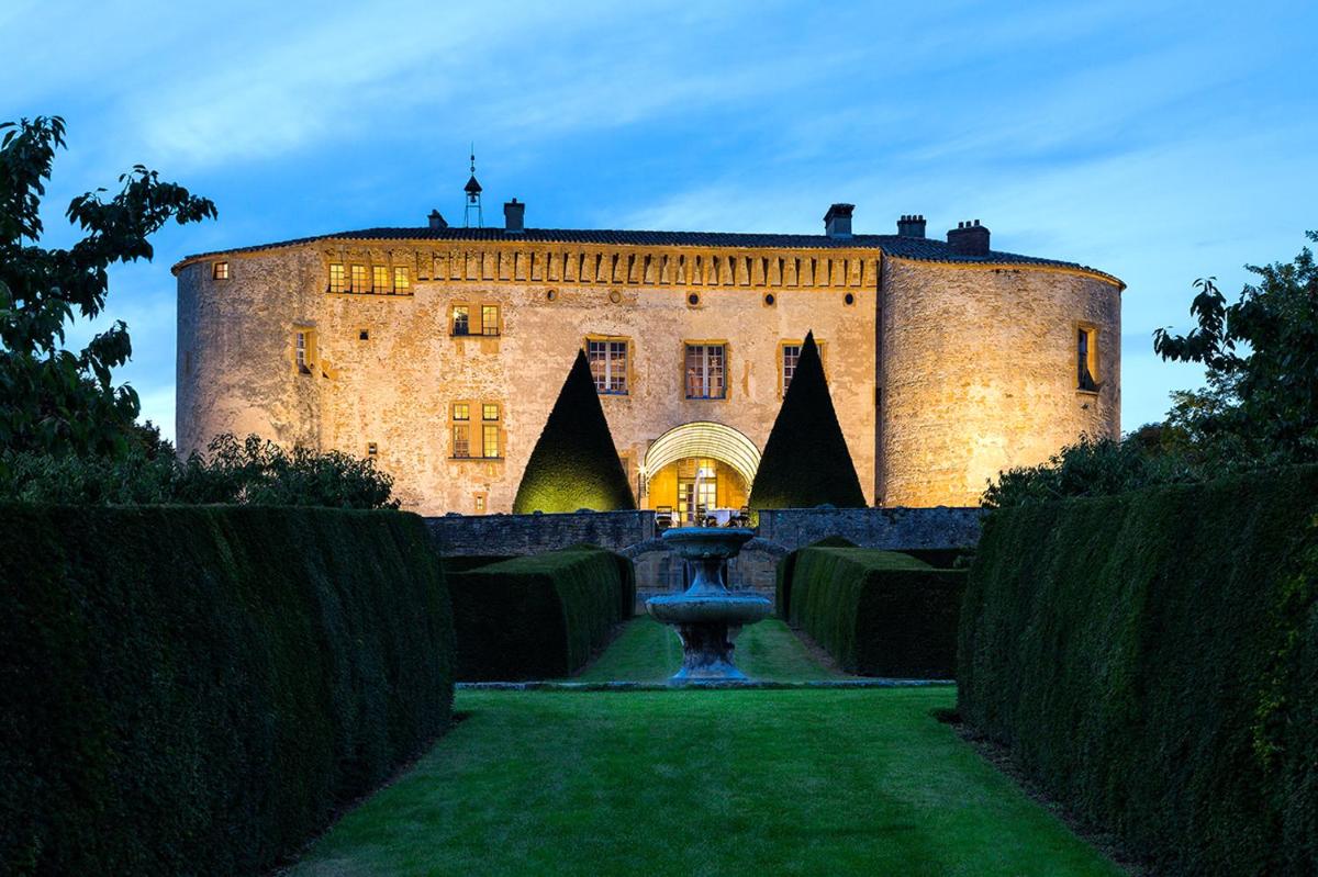 un château avec une fontaine en face dans l'établissement Château de Bagnols, à Bagnols