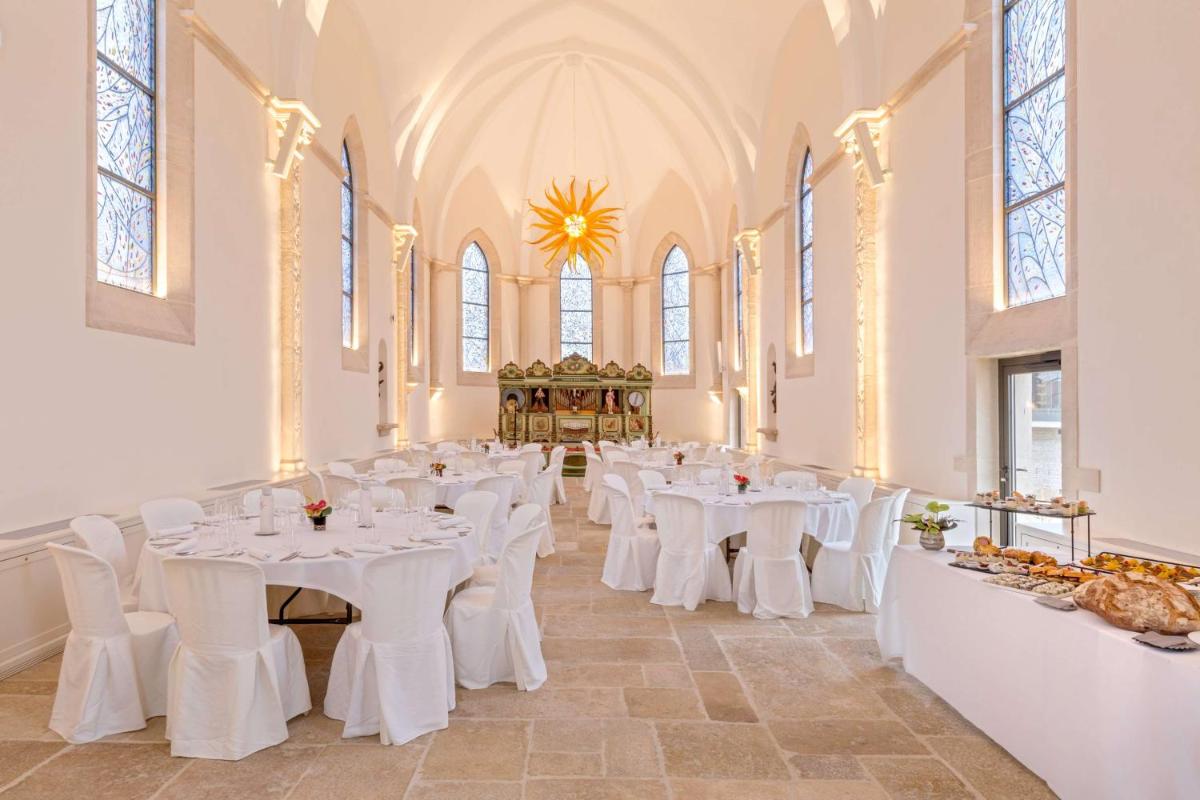 une chambre avec des tables et des chaises blanches dans une église dans l'établissement Hôtel & Spa Les Sept Fontaines Best Western Premier, à Tournus