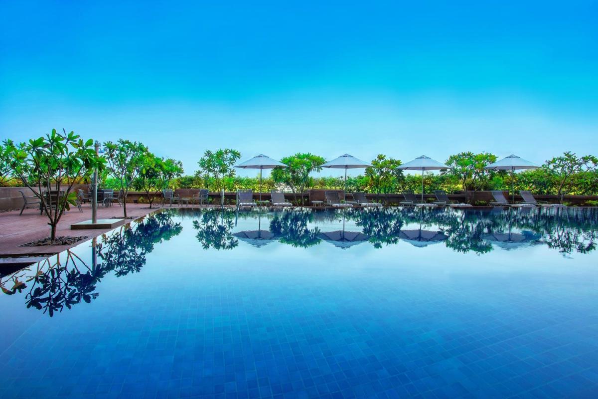 a swimming pool at a resort with chairs and trees at Crowne Plaza Ahmedabad City Centre by IHG in Ahmedabad