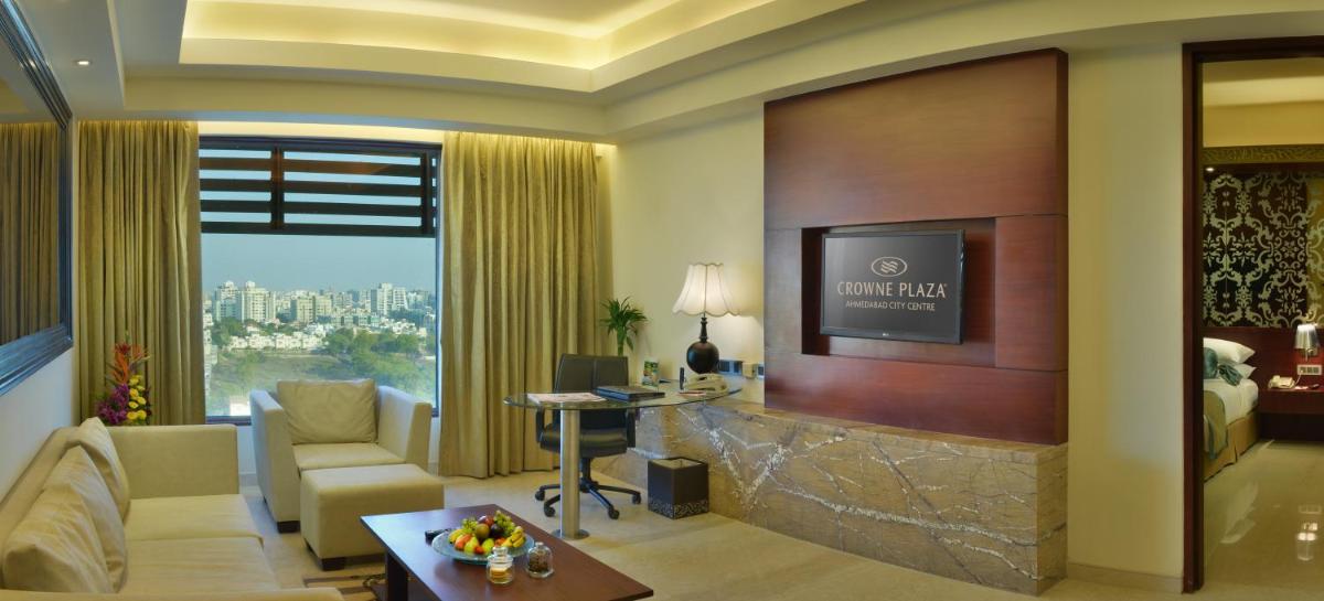 a living room with a tv and a couch and a table at Crowne Plaza Ahmedabad City Centre by IHG in Ahmedabad