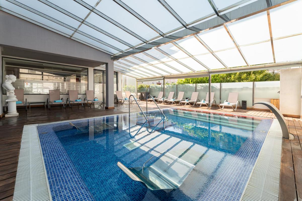 una piscina cubierta con techo de cristal y una piscina en Nautic Hotel & Spa, en Can Pastilla
